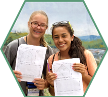 Two campers hold up papers on which  they drew the Blair Cabin.