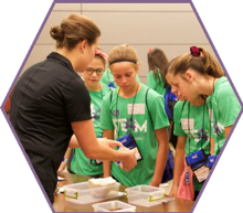 A Devon Energy employee shares fossils and different types or rocks with a group of campers.