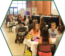 Small groups of campers interact with small groups of professional women at different tables at the STEAMentor event