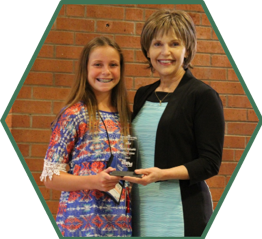 A camp sponsor presents a camper with an award during the graduation ceremony.