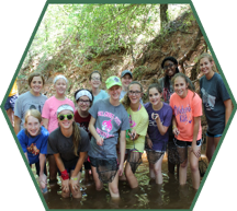 A group of campers pose proudly in the creek with the water samples they collected from the creek.